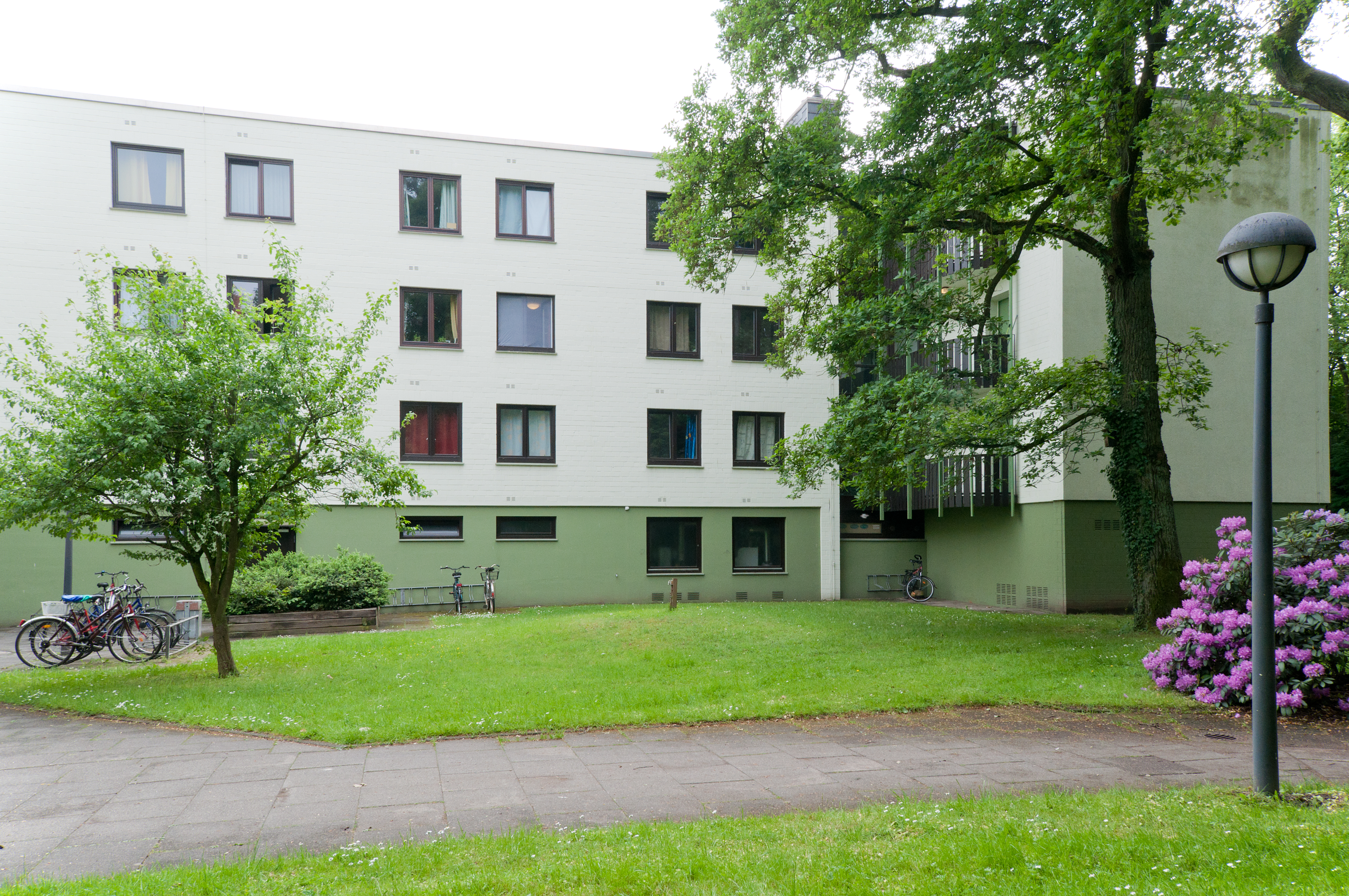 Außenansicht der Wohnanlage mit Bäumen und Wiese.